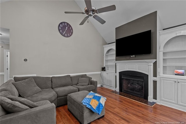 living room with ceiling fan, wood finished floors, vaulted ceiling, built in shelves, and a fireplace