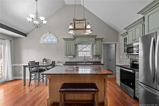 kitchen with a center island, decorative light fixtures, green cabinets, appliances with stainless steel finishes, and a sink