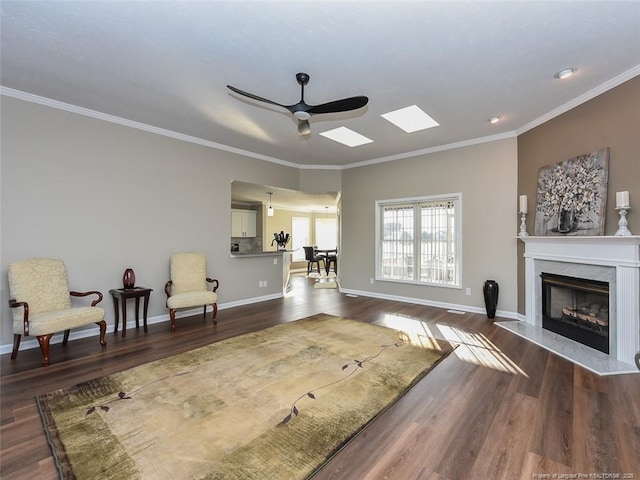 sitting room featuring dark wood-style flooring, a fireplace, a ceiling fan, baseboards, and ornamental molding