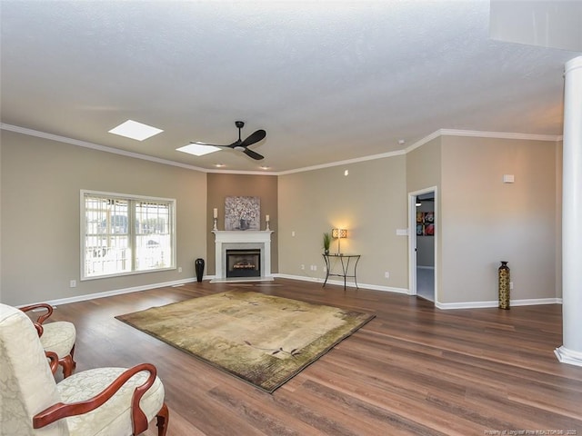 living room with crown molding, a fireplace, dark wood-type flooring, ceiling fan, and baseboards