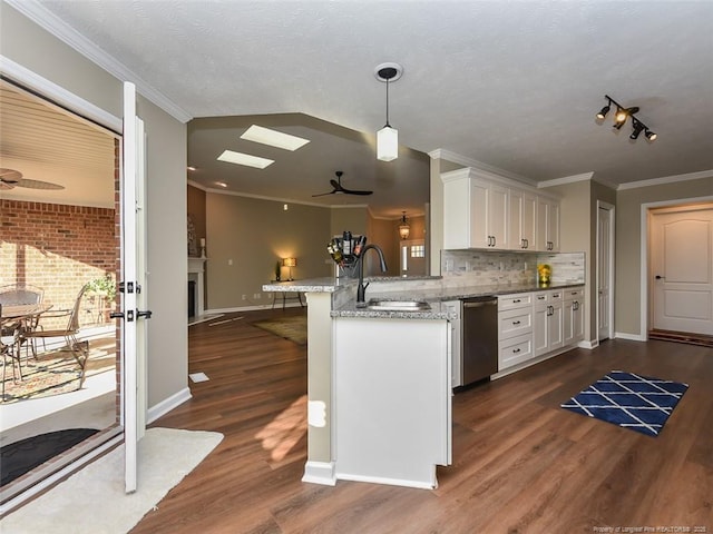 kitchen with a fireplace, a breakfast bar area, hanging light fixtures, white cabinets, and a sink