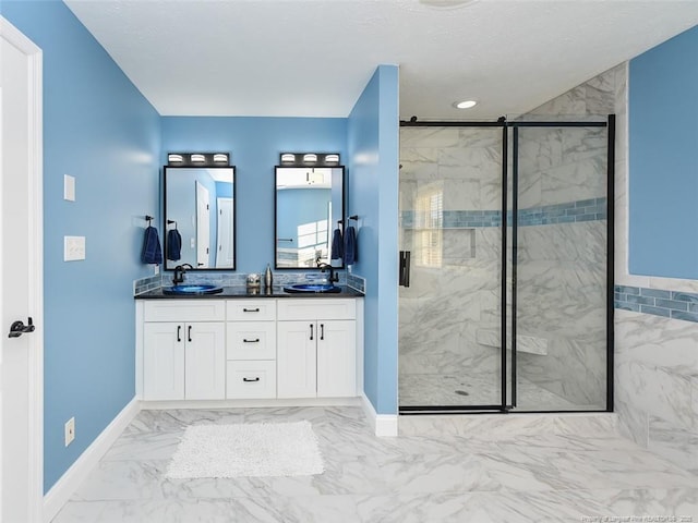 full bathroom featuring double vanity, marble finish floor, a marble finish shower, and a sink