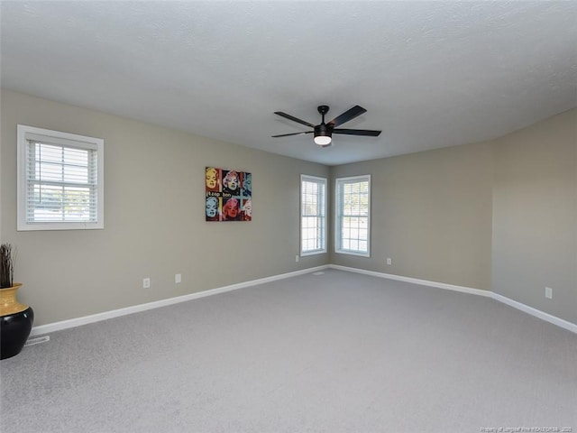 carpeted spare room with visible vents, ceiling fan, a textured ceiling, and baseboards