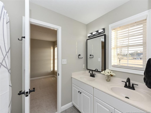 bathroom with a sink, baseboards, and double vanity