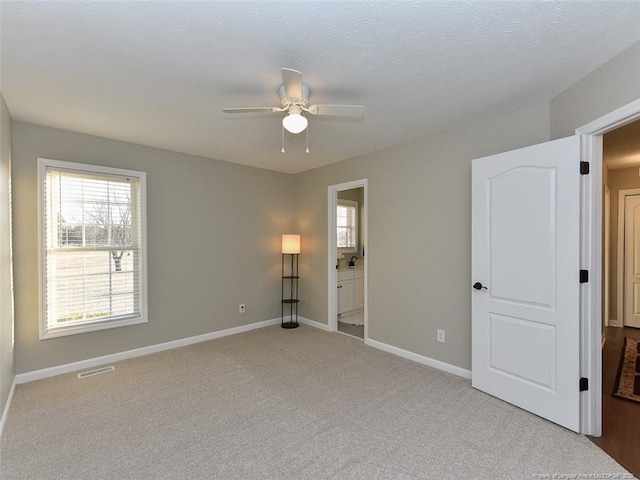 unfurnished bedroom featuring carpet floors, multiple windows, visible vents, and baseboards