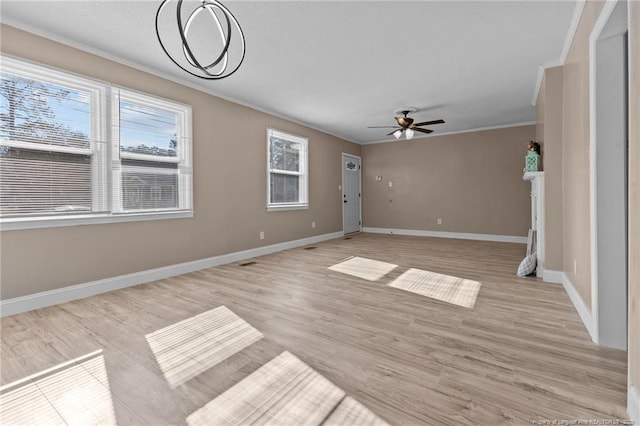 unfurnished living room with ceiling fan, a fireplace, baseboards, light wood finished floors, and crown molding