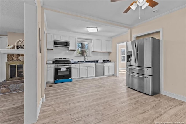 kitchen with stainless steel appliances, a sink, white cabinetry, light wood-type flooring, and crown molding