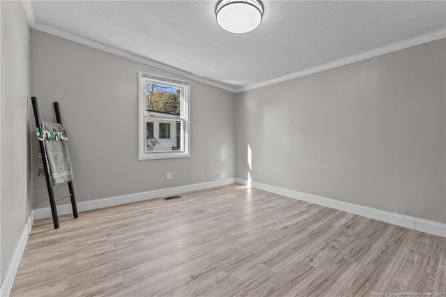 empty room with ornamental molding, light wood-type flooring, visible vents, and a textured ceiling