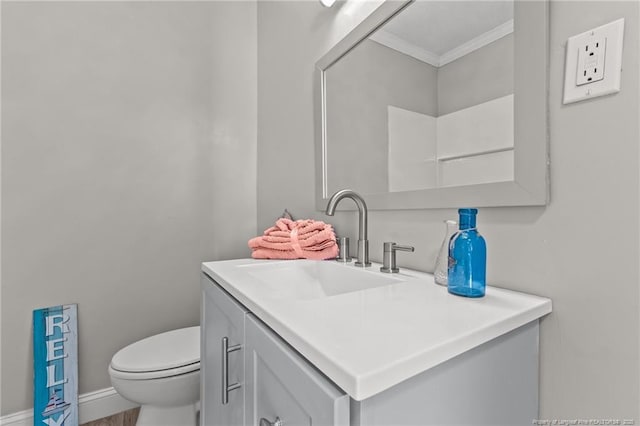 bathroom with toilet, baseboards, vanity, and crown molding