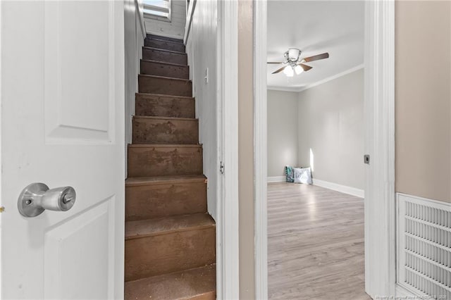 stairway featuring baseboards, visible vents, a ceiling fan, wood finished floors, and crown molding