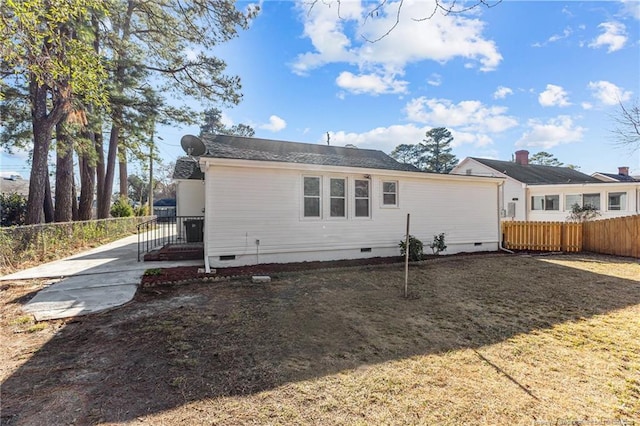 back of house with crawl space, fence, and a lawn