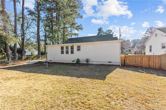 back of house featuring crawl space, a fenced backyard, and a lawn