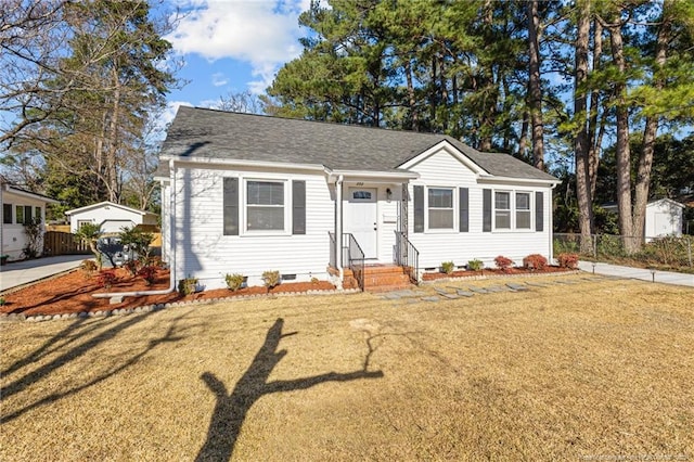 view of front facade with an outbuilding, roof with shingles, crawl space, and a front yard