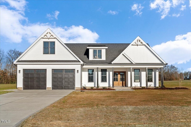 modern farmhouse featuring a shingled roof, an attached garage, board and batten siding, a front yard, and driveway