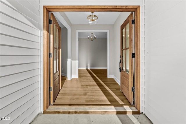 hall featuring baseboards and a notable chandelier