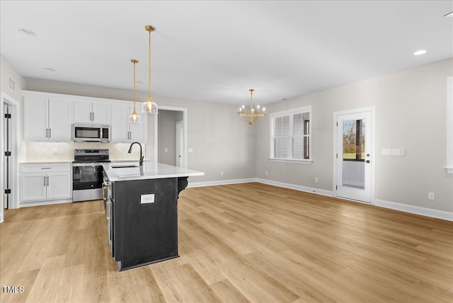 kitchen with light countertops, appliances with stainless steel finishes, light wood-type flooring, and a sink