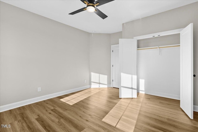 unfurnished bedroom featuring a closet, wood finished floors, a ceiling fan, and baseboards