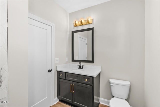 half bathroom featuring vanity, toilet, and baseboards