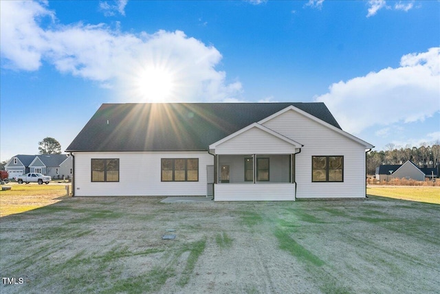 rear view of property with a sunroom and a lawn