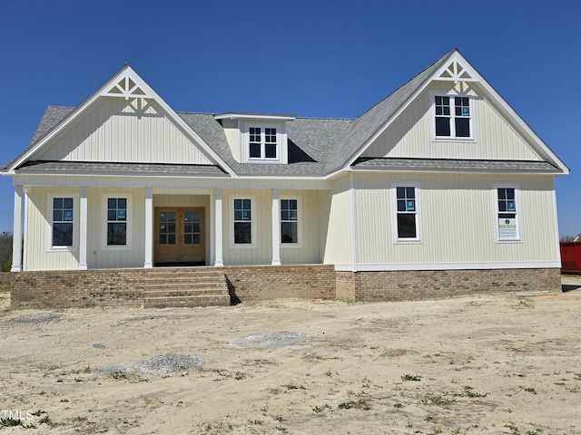 modern inspired farmhouse with french doors, a porch, and roof with shingles
