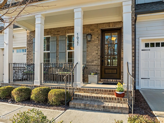 entrance to property with a porch, a shingled roof, and brick siding