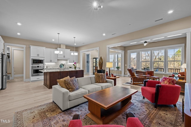 living area featuring light wood finished floors, baseboards, visible vents, ceiling fan, and recessed lighting