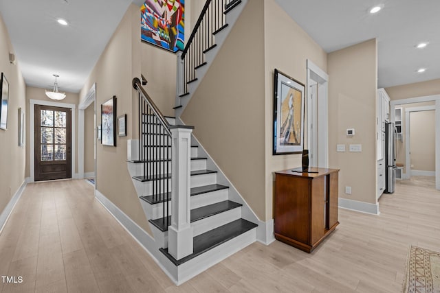 entrance foyer with baseboards, light wood finished floors, stairway, and recessed lighting