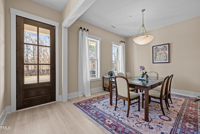 dining area featuring a healthy amount of sunlight, light wood-type flooring, and baseboards