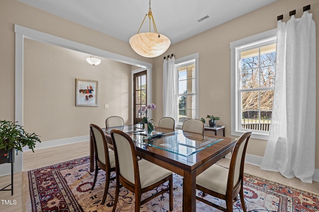 dining space with light wood-style flooring, visible vents, and baseboards