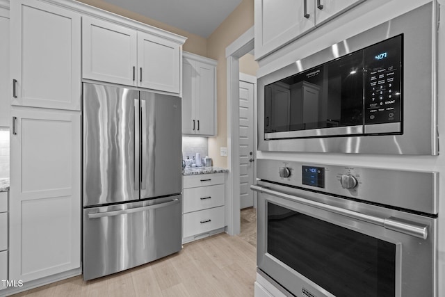 kitchen featuring light wood-style floors, white cabinetry, appliances with stainless steel finishes, and light stone counters