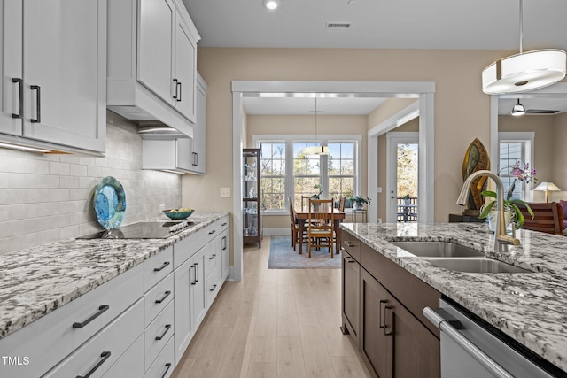 kitchen with black electric stovetop, visible vents, light wood-style floors, a sink, and dishwasher