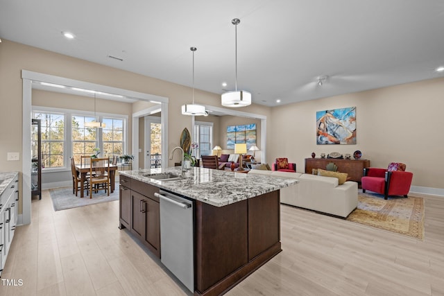 kitchen with dishwasher, a sink, dark brown cabinetry, and light wood-style floors