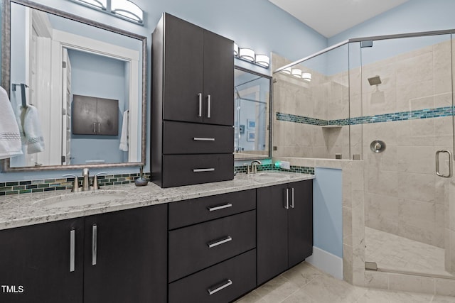 bathroom with double vanity, a stall shower, tasteful backsplash, and a sink