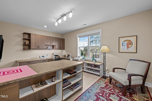 kitchen featuring open shelves, rail lighting, visible vents, light wood-style flooring, and baseboards