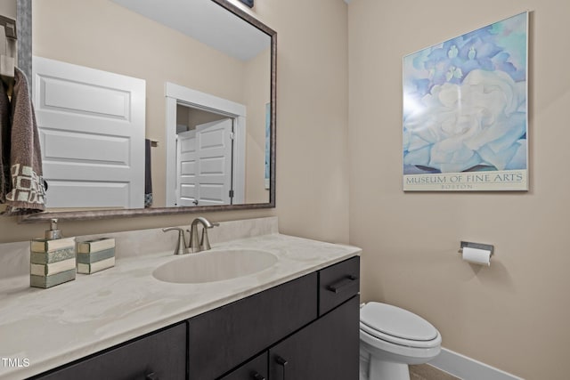 bathroom featuring vanity, toilet, and baseboards