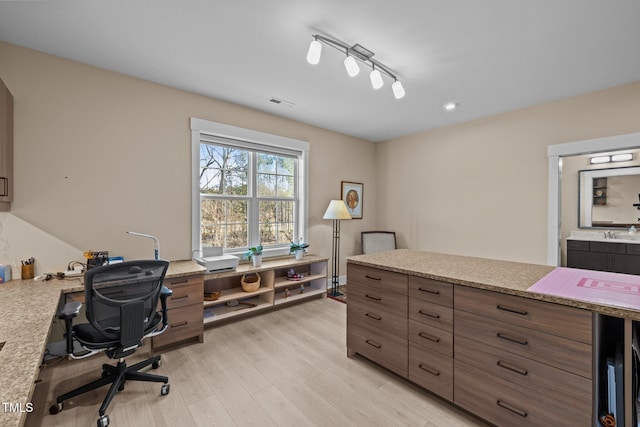 office space featuring light wood-style floors, rail lighting, visible vents, and a sink