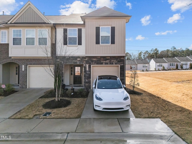 multi unit property featuring concrete driveway, an attached garage, board and batten siding, and stone siding