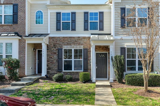 townhome / multi-family property featuring a standing seam roof, stone siding, and metal roof