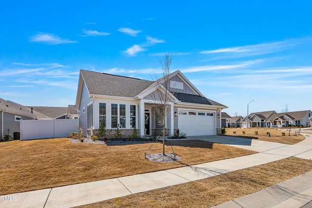 view of front of home featuring concrete driveway, fence, a front lawn, board and batten siding, and brick siding