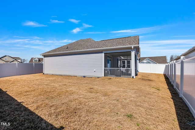 rear view of property with a fenced backyard, a yard, and roof with shingles