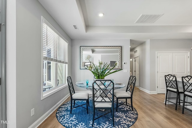 dining room featuring light wood finished floors, baseboards, and visible vents