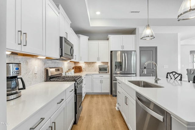 kitchen featuring light countertops, appliances with stainless steel finishes, a sink, and white cabinetry