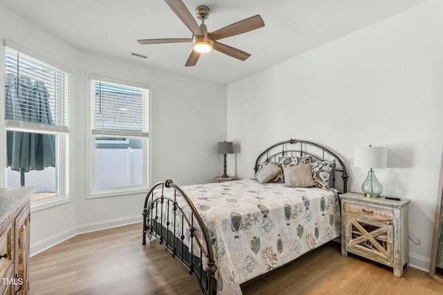 bedroom with ceiling fan, light wood-type flooring, visible vents, and baseboards