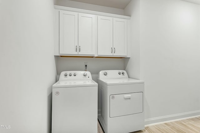 washroom featuring light wood-type flooring, cabinet space, baseboards, and washer and clothes dryer