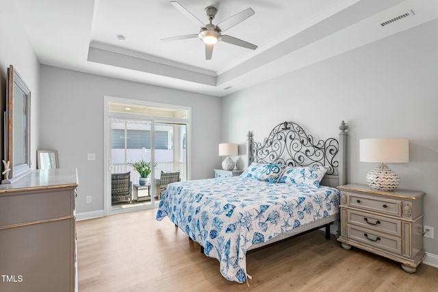 bedroom featuring a tray ceiling, access to outside, visible vents, and light wood-style flooring