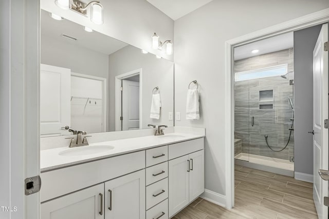 bathroom with a stall shower, a walk in closet, a sink, and double vanity