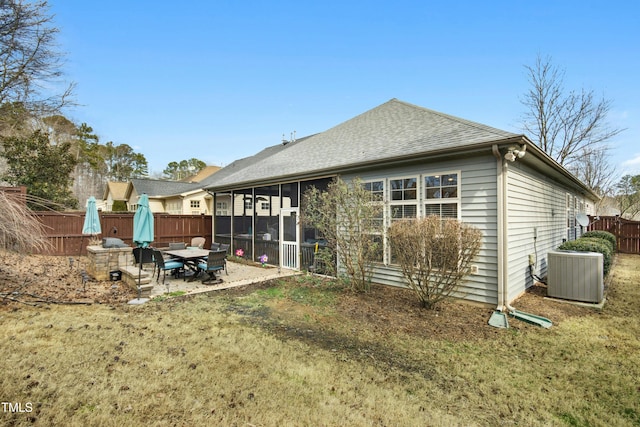 rear view of property featuring a fenced backyard, central air condition unit, a shingled roof, a sunroom, and a patio area