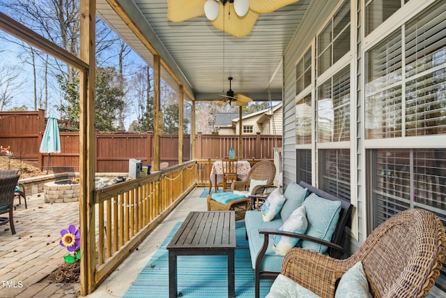 deck with ceiling fan, an outdoor living space with a fire pit, and fence