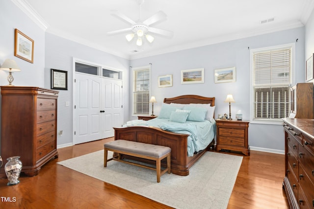 bedroom with ornamental molding, a closet, wood finished floors, and visible vents