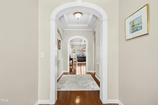 corridor with baseboards, visible vents, arched walkways, ornamental molding, and wood finished floors